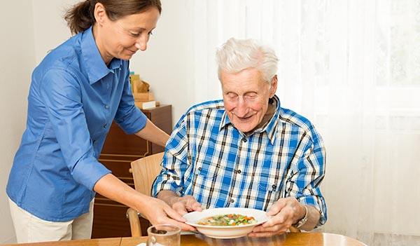 Nurse giving senior man lunch