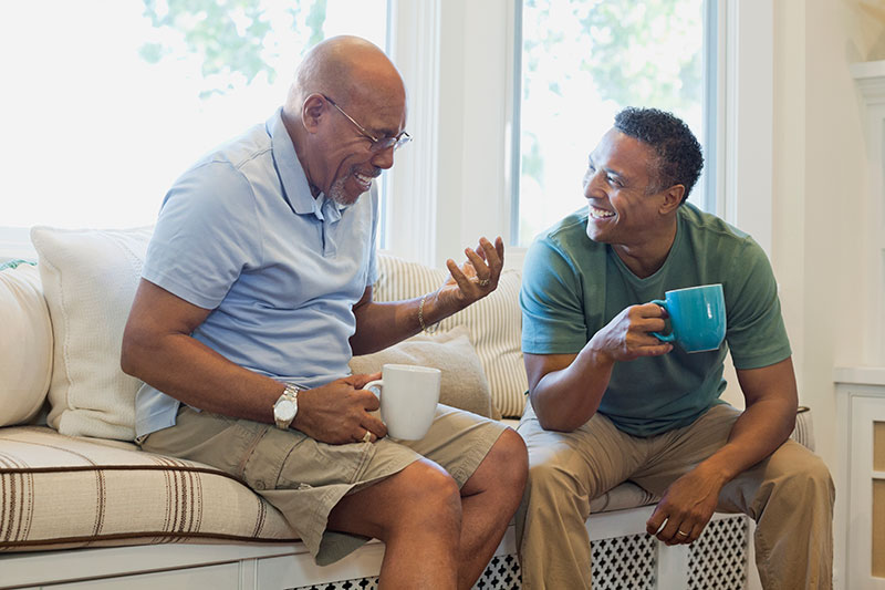 A son laughs with his father as he uses tips to manage repetitive questions in dementia.