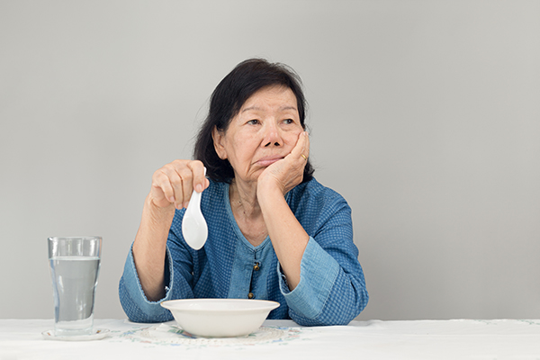 Elderly asian woman bored with food