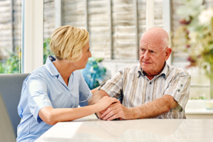 Senior man sitting with female caregiver, home care services huntington beach