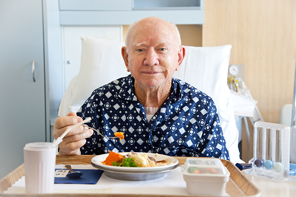 Senior man patient in hospital eating lunch