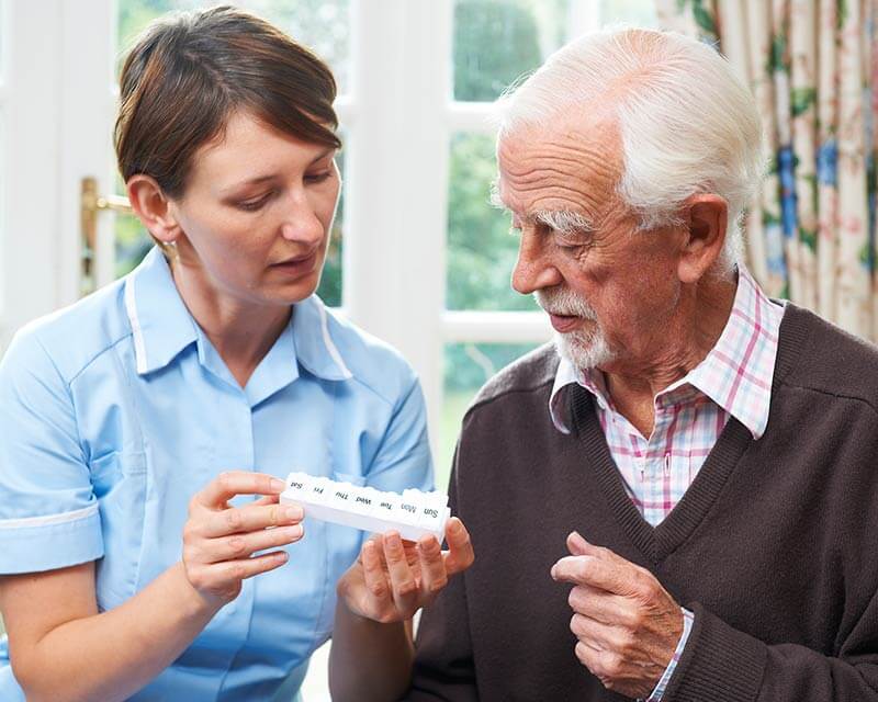 Caregiver showing client how to use a pill box