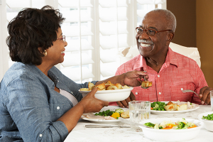 A senior couple sitting at a dinner table eating