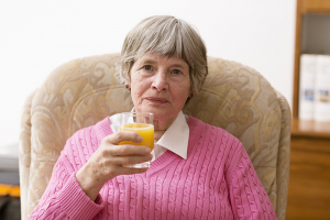 senior woman drinking orange juice at home