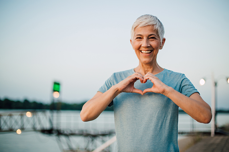 happy senior woman making a heart shape with her hands