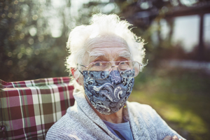 Friendly old senior wears a mask to protect against viruses and bacteria