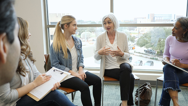 With a serious look on her face, the teen girl looks at her grandmother during group therapy.