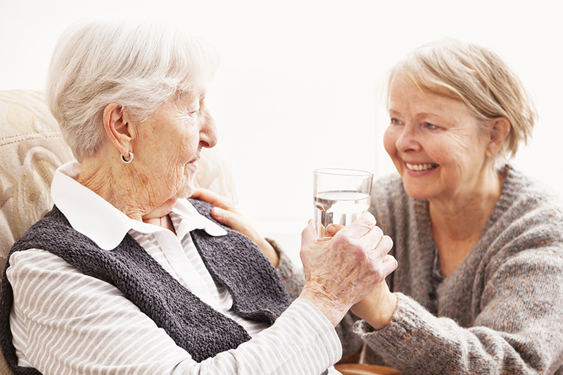 caregiver giving senior woman a glass of water