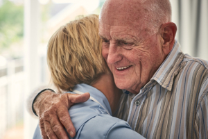 Female home carer hugging senior male patient at care home