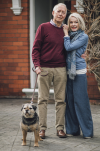 senior with dementia and wife outside their home with dog