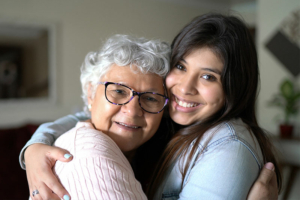 happy latino senior hugging caregiver