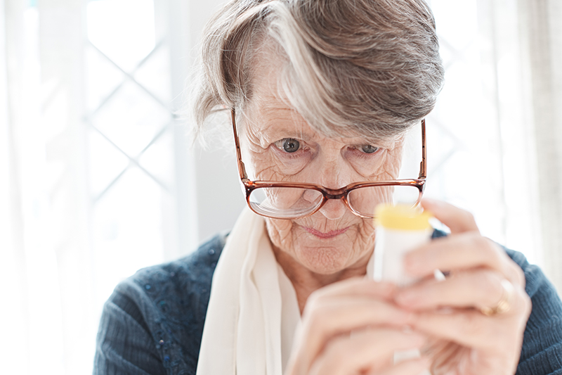 senior lady looking at medicine bottle