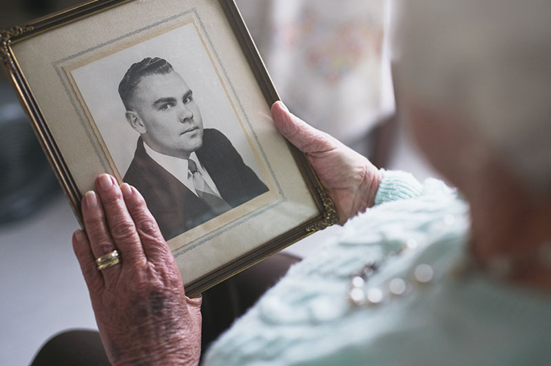 senior lady with broken heart looking at old photo