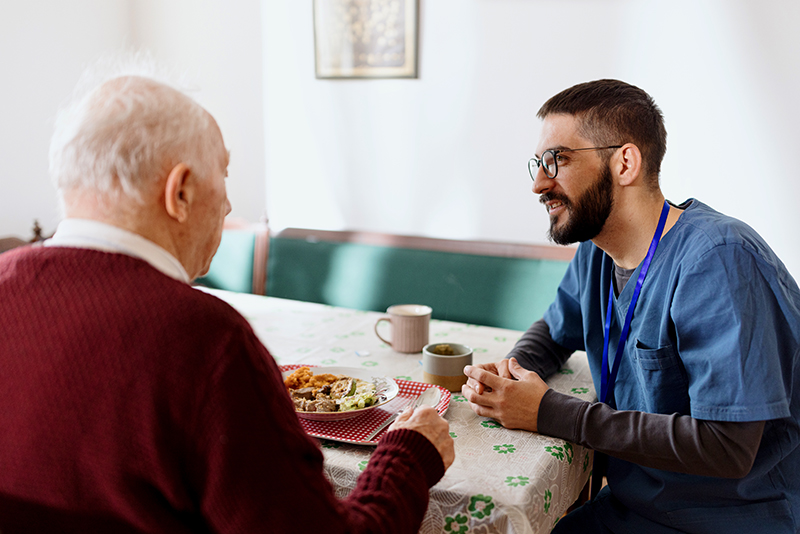 senior man with caregiver at table