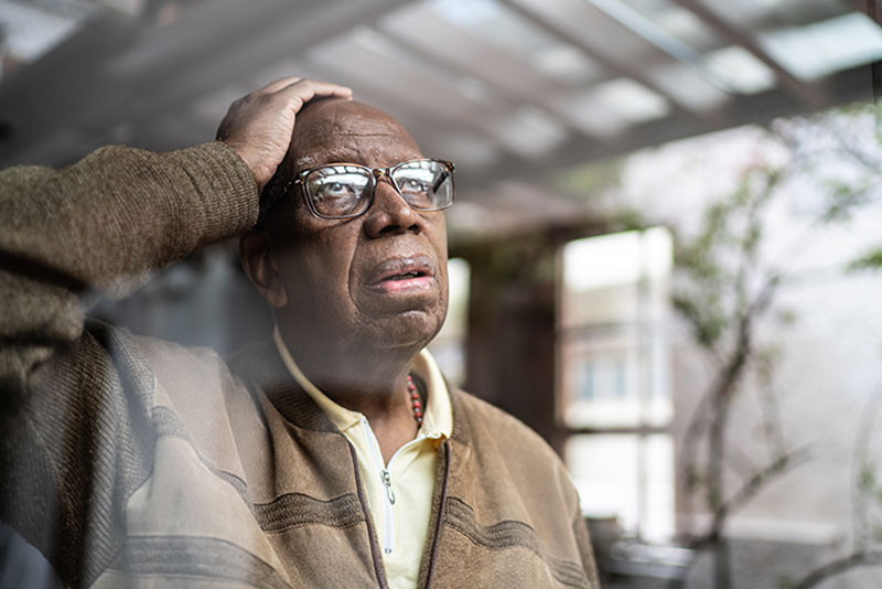 confused senior man looking out window