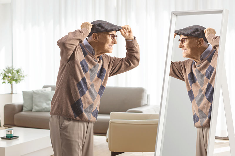 A man looks in the mirror as he tries on adaptive clothing for seniors.