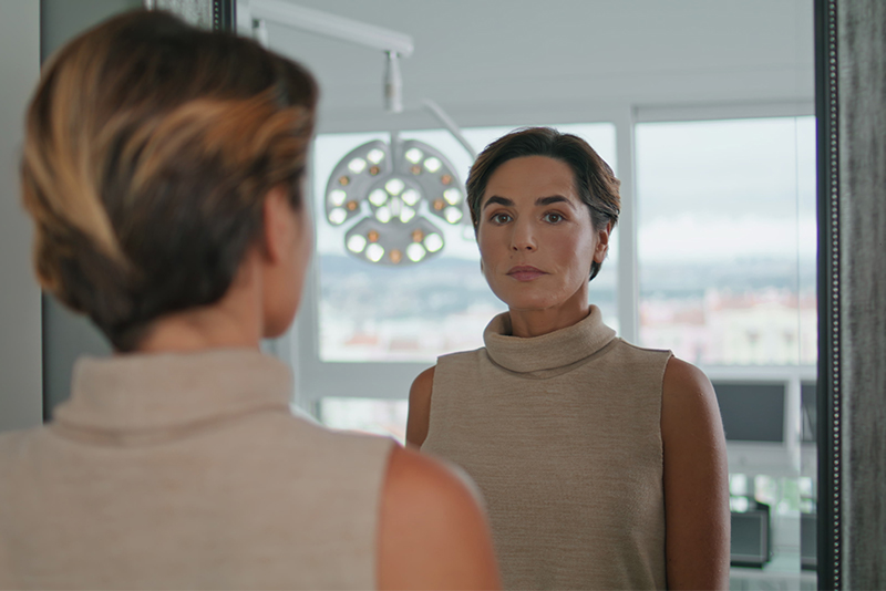 A woman examines her reflection in the mirror as she contemplates her journey after caregiving.