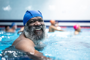 A senior man who knows how much exercise older adults need works out in a swimming pool.