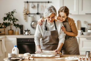 A woman bakes in the kitchen with her elderly mother as part of their dementia care routine.