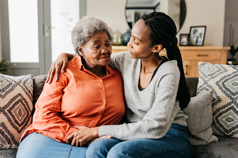 A woman comforts her elderly mother as she contemplates whether it is time for 24-hour dementia care.