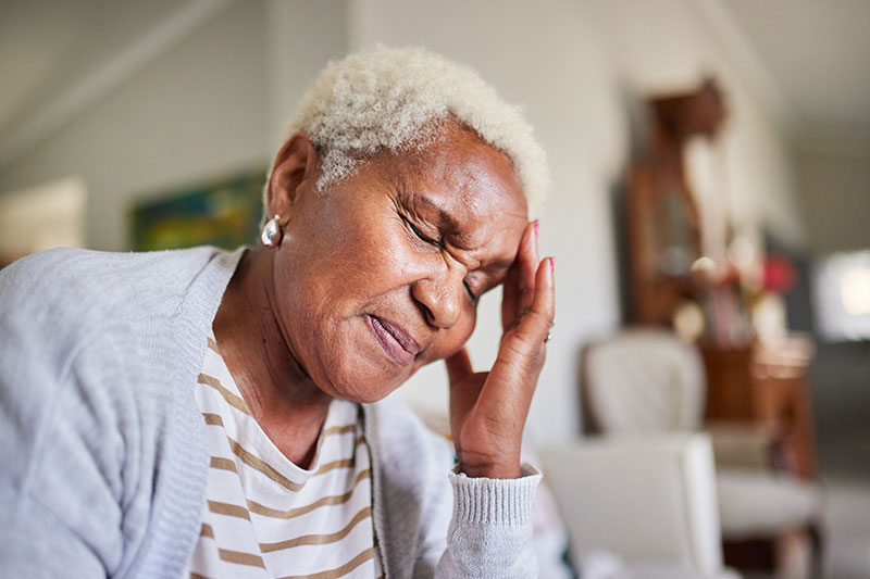 A woman who struggles with headaches from COPD winces as she touches her forehead.