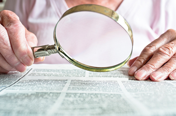 older person holding a magnifying glass to read