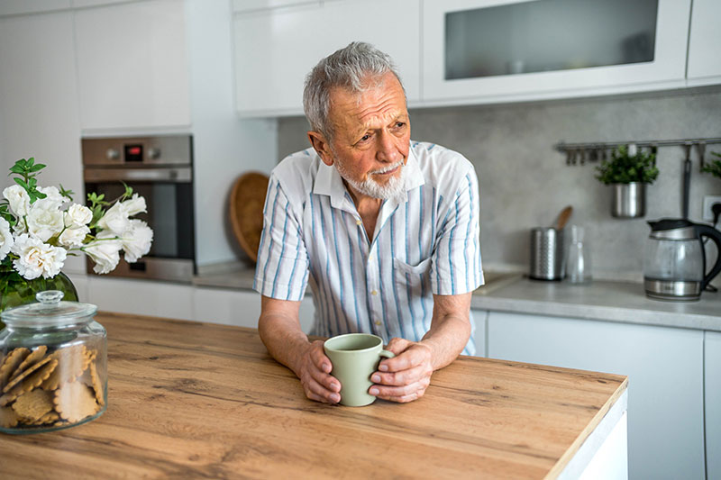 A man experiencing Parkinson’s mood changes leans on his counter while holding a cup of coffee.