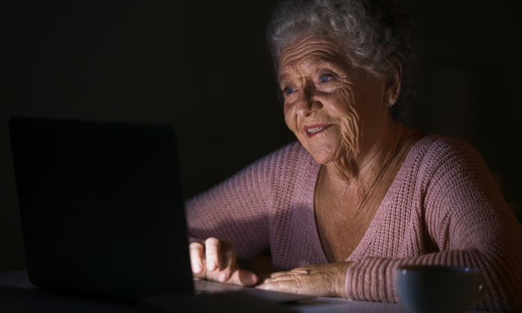 Senior woman awake at night using a laptop while receiving overnight home care support