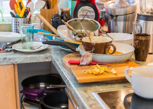 Pile of dirty dishes in the sink as a warning sign an aging parent may need help at home